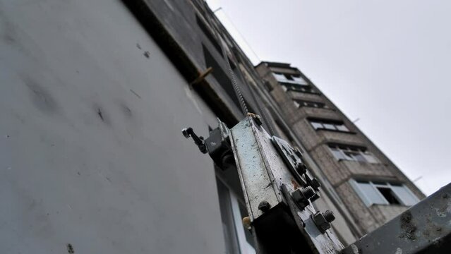 Close-up of the winch of the construction elevator on the background of a multi-storey building. Elevator for carrying out outdoor repair work of multi-apartment high-rise buildings.