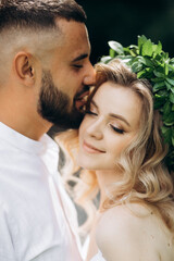 A happy young couple in love walk in a garden. A man in a white shirt and a girl in a white light dress are walking in a park