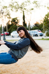 Young spanish asian woman plays in a child park, having fun and smiling