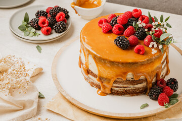 Delicious chocolate cake topped with mascarpone cream and salted caramel. Decorated with red fruits. Light background