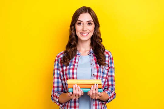 Portrait of satisfied intelligent nice woman with curly hairstyle wear checkered shirt hold book isolated on yellow color background