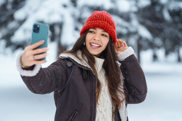 Young woman taking selfie in winter forest. Holidays, rest, travel concept.