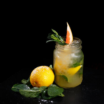 Mason Jar Of Tasty Cold Lemonade Decorated With Grapefruit, Lemon And Mint On Black Background.