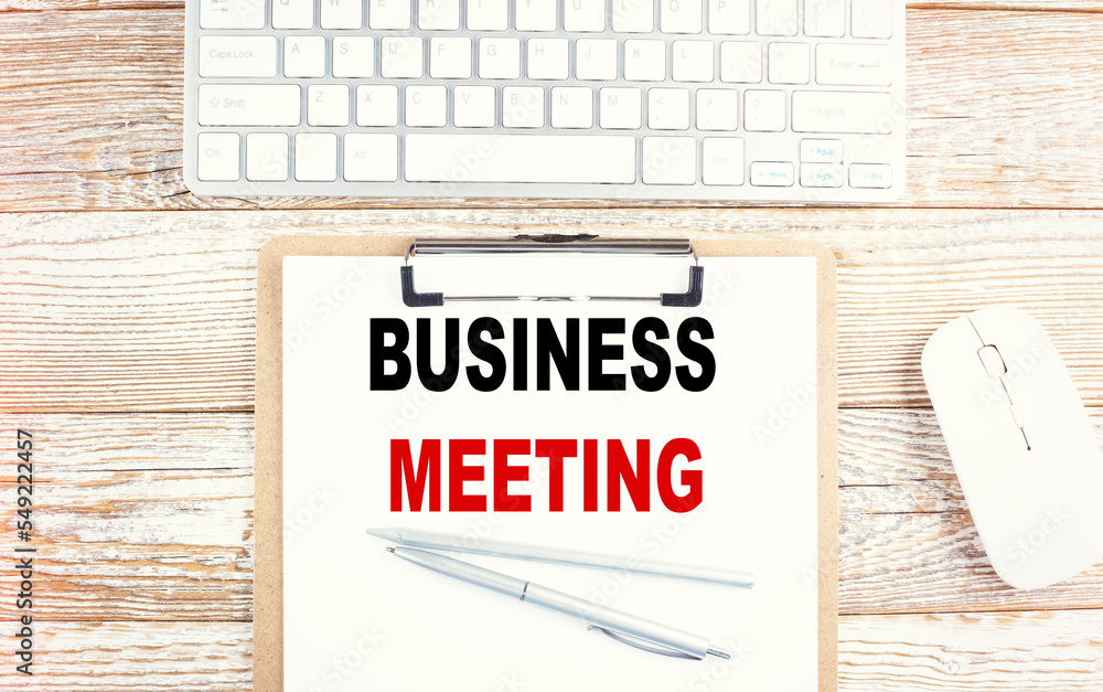 Poster minutes of the meeting text on a clipboard with keyboard on wooden background