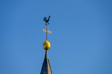 Fototapeta na wymiar Kirchturmspitze mit Wetterhahn, Kreuz und Turmkugel vor blauem Himmel
