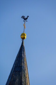 Kirchturmspitze mit Wetterhahn, Kreuz und Turmkugel vor blauem Himmel