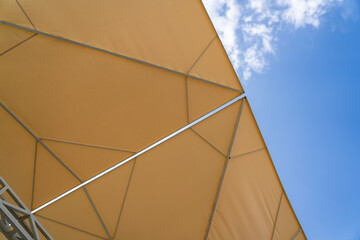 Sunprotecting awning from fabric material against blue sunny sky