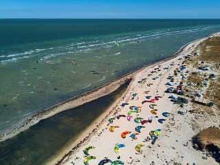 View from above of bright colorful kites lying parked on beach on windy day at kitesurfing spot. A...