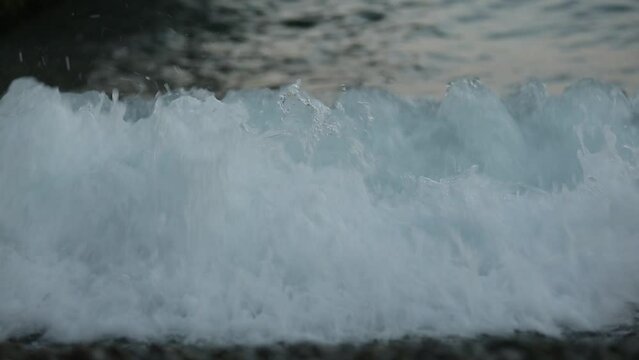 Gorgeous view of sea waves surge and break into the rocky shoreline. Ocean waves running towards a rocky ocean shore during tide closeup shot. Skipper's daughters. White horses. Waves with white foam