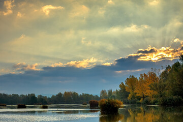 Fototapeta premium Sunrise over lake, sun hidden behind a cloud. Autumn landscape. Dubnica, Slovakia.