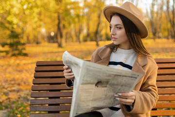 An attractive girl reads a newspaper in the park. Surveillance private detective monitors the...