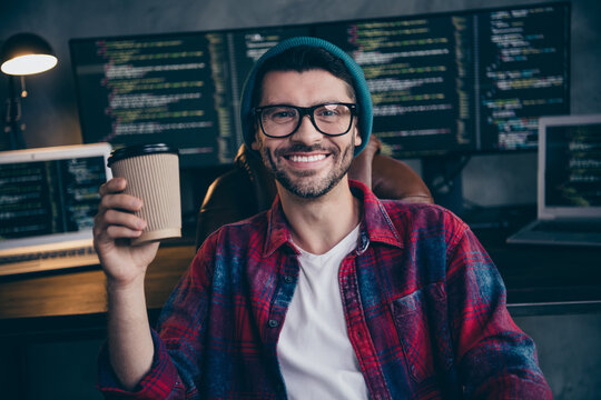 Photo of happy smiling freelancer wear hat glasses having pause drinking beverage indoors workplace workstation loft