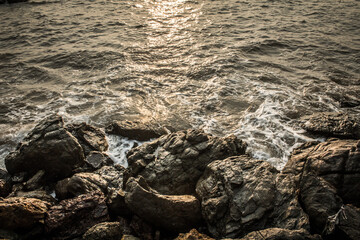 Sea waves hit the rock splash on the coast at the sunset