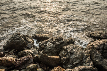Sea waves hit the rock splash on the coast at the sunset