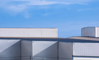 Fototapeta na wymiar High section of modern corrugated iron industrial factory Buildings against blue sky background 