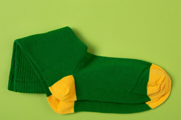 A pair of green socks with yellow toes and heels, on a green background