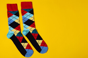 A pair of colored socks with rhombuses, on a yellow background