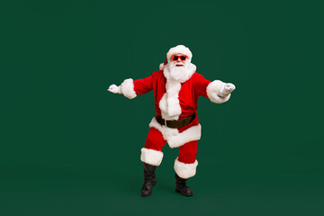 Full size photo of funky santa claus with grey beard listen x-mas christmas music song headset dance wear sunglass headwear cap isolated over bright shine color background