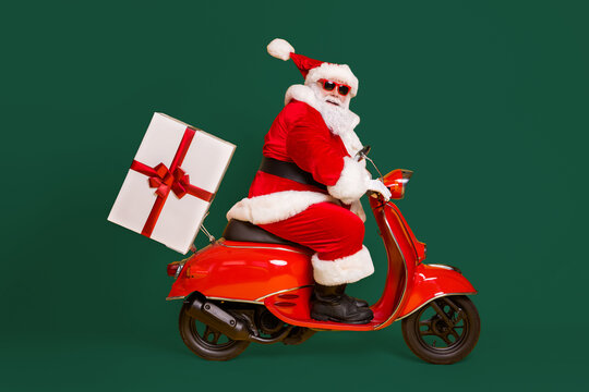 Full length profile side photo of grey white hair bearded santa claus ride drive bike deliver gift box x-mas christmas night wear red headwear isolated yellow color background