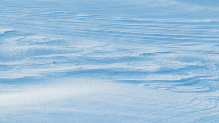Snowy background, snow-covered surface of the earth after a blizzard in the morning in the sunlight with distinct layers of snow