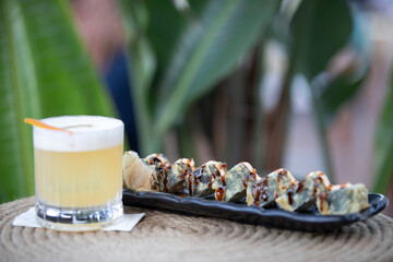 Sushi plate with cocktail on the table.