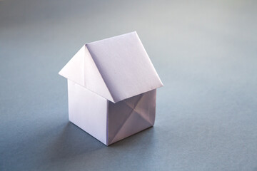 White paper house origami isolated on a grey background