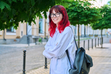 Portrait of smiling female student 18, 19 years old on city street