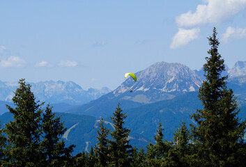 a paraglider flying over the vast alpine valley surrounded by the Austrian Alps of the...