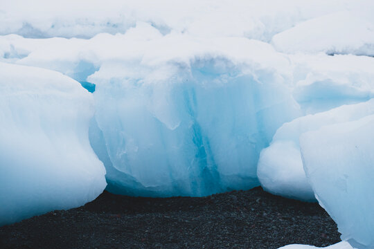 Close up on ice chunk, with the blue colors and covered with snow.  Image was taken on a beach in Antarctica. 