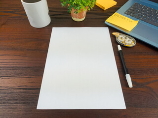 Flat lay, a mockup of a notebook. A workspace with white notebooks, laptops, office supplies, pencils, and coffee cups in the office background of a wooden desk from top view.