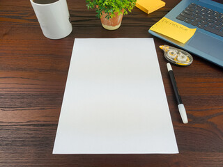 Flat lay, a mockup of a notebook. A workspace with white notebooks, laptops, office supplies, pencils, and coffee cups in the office background of a wooden desk from top view.