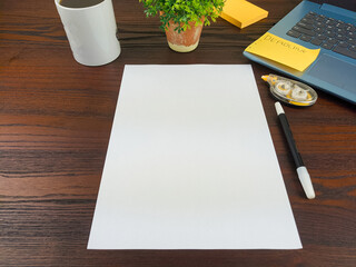 Flat lay, a mockup of a notebook. A workspace with white notebooks, laptops, office supplies, pencils, and coffee cups in the office background of a wooden desk from top view.