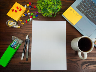 Flat lay, a mockup of a notebook. A workspace with white notebooks, laptops, office supplies, pencils, and coffee cups in the office background of a wooden desk from top view.