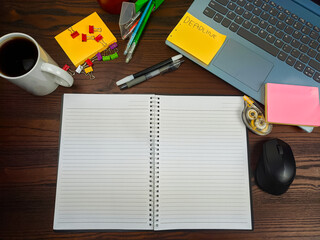 Flat lay, a mockup of a notebook. A workspace with white notebooks, laptops, office supplies,and coffee cups in the office background of a wooden desk from top view.