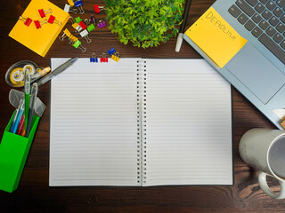 Flat lay, a mockup of a notebook. A workspace with white notebooks, laptops, office supplies, pencils, and coffee cups in the office background of a wooden desk from top view.