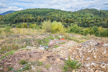 Garbage dump in the mountains. Half-buried garbage in the wooded mountains. Carpathians. Ukraine