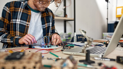 Man connecting wires with microchip and voltmeter
