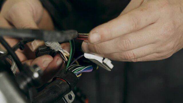 The mechanic sorts out chips for connecting electrical equipment in a motorcycle. Close-up. Transport concept