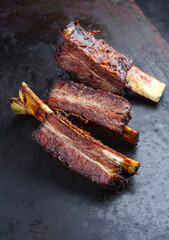 Traditional barbecue burnt chuck short beef ribs marinated with spicy rub and served with a hot chili sauce as close-up on a rustic board