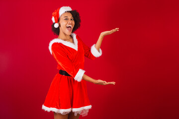 beautiful black brazilian woman, dressed as santa claus, mama claus, presenting product or information on the side