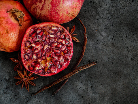 open juicy pomegranate and spices on wooden background