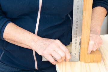 Carpintero colocando una pata de la mesa de madera recta, con la ayuda de una escuadra de metal