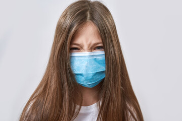 Angry little girl wear medical mask look at camera