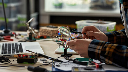 Side of cropped male engineer soldering microchip