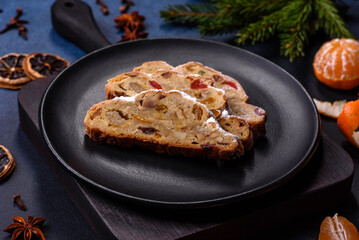 Delicious festive New Year's pie with candied fruits, marzipan and nuts on a dark concrete background