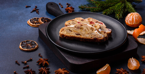 Delicious festive New Year's pie with candied fruits, marzipan and nuts on a dark concrete background
