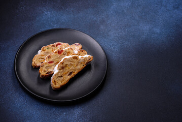 Delicious festive New Year's pie with candied fruits, marzipan and nuts on a dark concrete background
