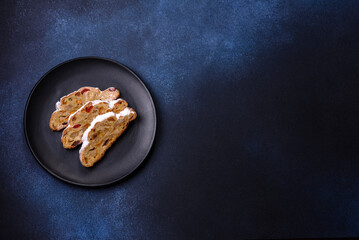 Delicious festive New Year's pie with candied fruits, marzipan and nuts on a dark concrete background