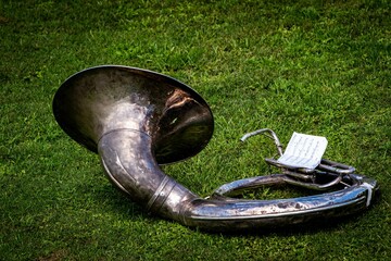 Old sousaphone with a piece of little sheet music, isolated on the grass in a park