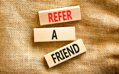 Refer a friend symbol. Concept words Refer a friend on wooden blocks on a beautiful canvas table canvas background. Business and refer a friend concept. Copy space.